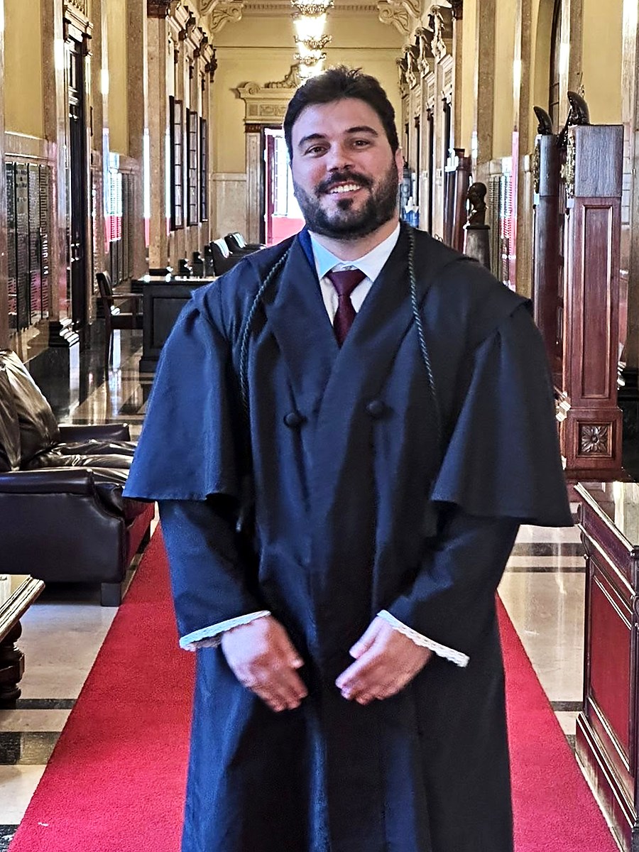 Retrato de Caio Regagnin, advogado, sorrindo e vestindo beca