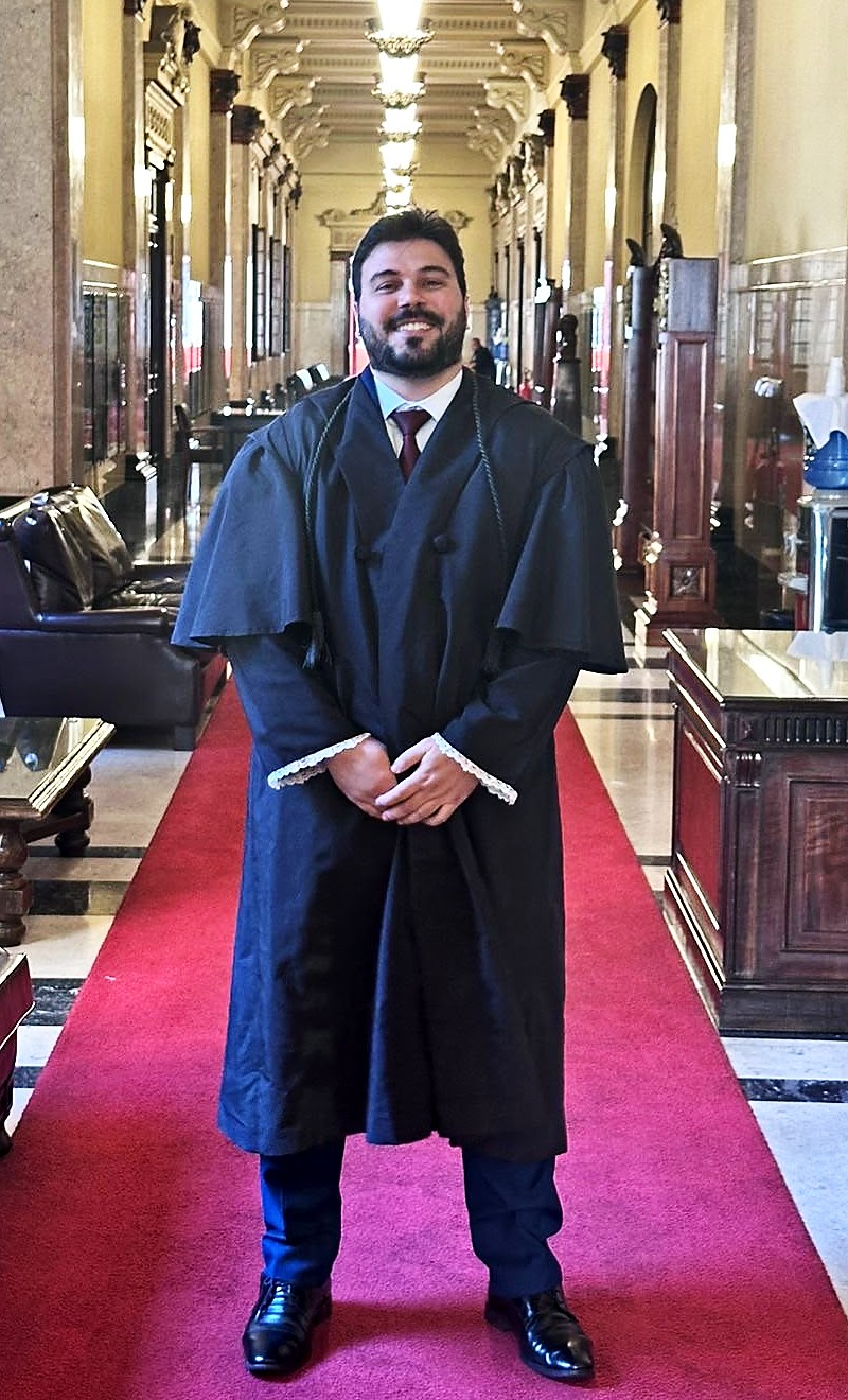 Caio Regagnin vestindo beca de advogado em corredor histórico de tribunal